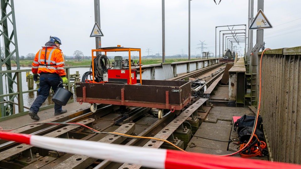 Ein Arbeiter steht auf einer gesperrten Eisenbahnbrücke.